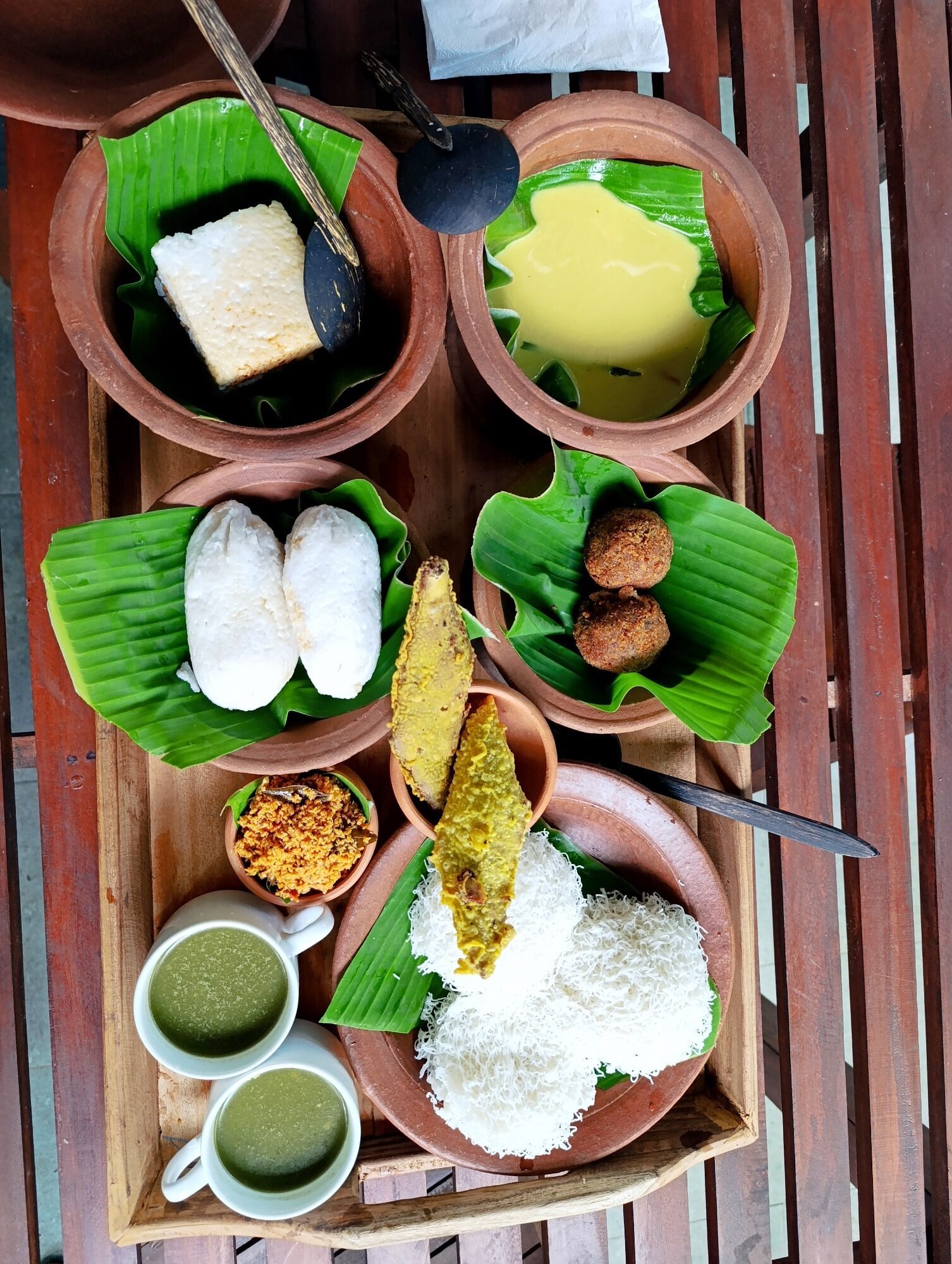 A tray with various traditional dishes, including rice, curries, and bread, served on banana leaves.