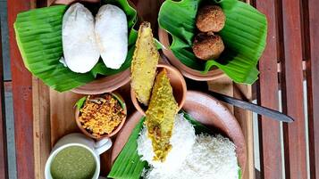 A tray with various traditional dishes, including rice, curries, and bread, served on banana leaves.