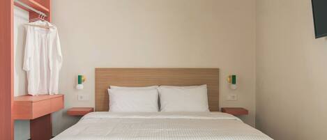 A neatly made bed with white linens, a wooden headboard, and a small bedside table with a lamp.