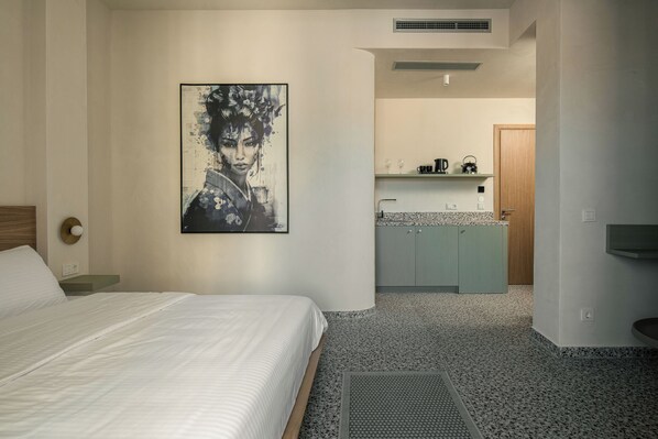 A hotel room with a bed, a bathroom with a sink, and a kitchen area.