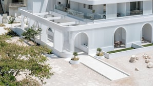 A modern, multi-story building with a flat roof, large windows, and a balcony. - FOS Luxury Suites (Nikiti)