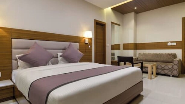 A modern hotel room with a large bed, a sofa, and a small table. - Hotel Blue Orchid (Udaipur)