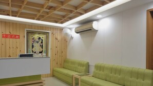 A reception area with a wooden ceiling, a green sofa, a small table, and a wall-mounted air conditioning unit. - Hotel Blue Orchid (Udaipur)