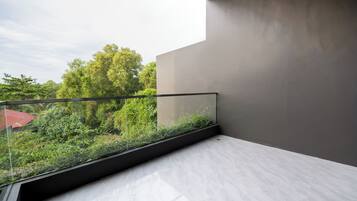 Un balcon donnant sur un paysage verdoyant et un bâtiment au toit rouge.