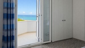 A room with a sliding glass door leading to a balcony with a view of the ocean. - Hotiday Castelsardo Spiaggia (Lu Bagnu)