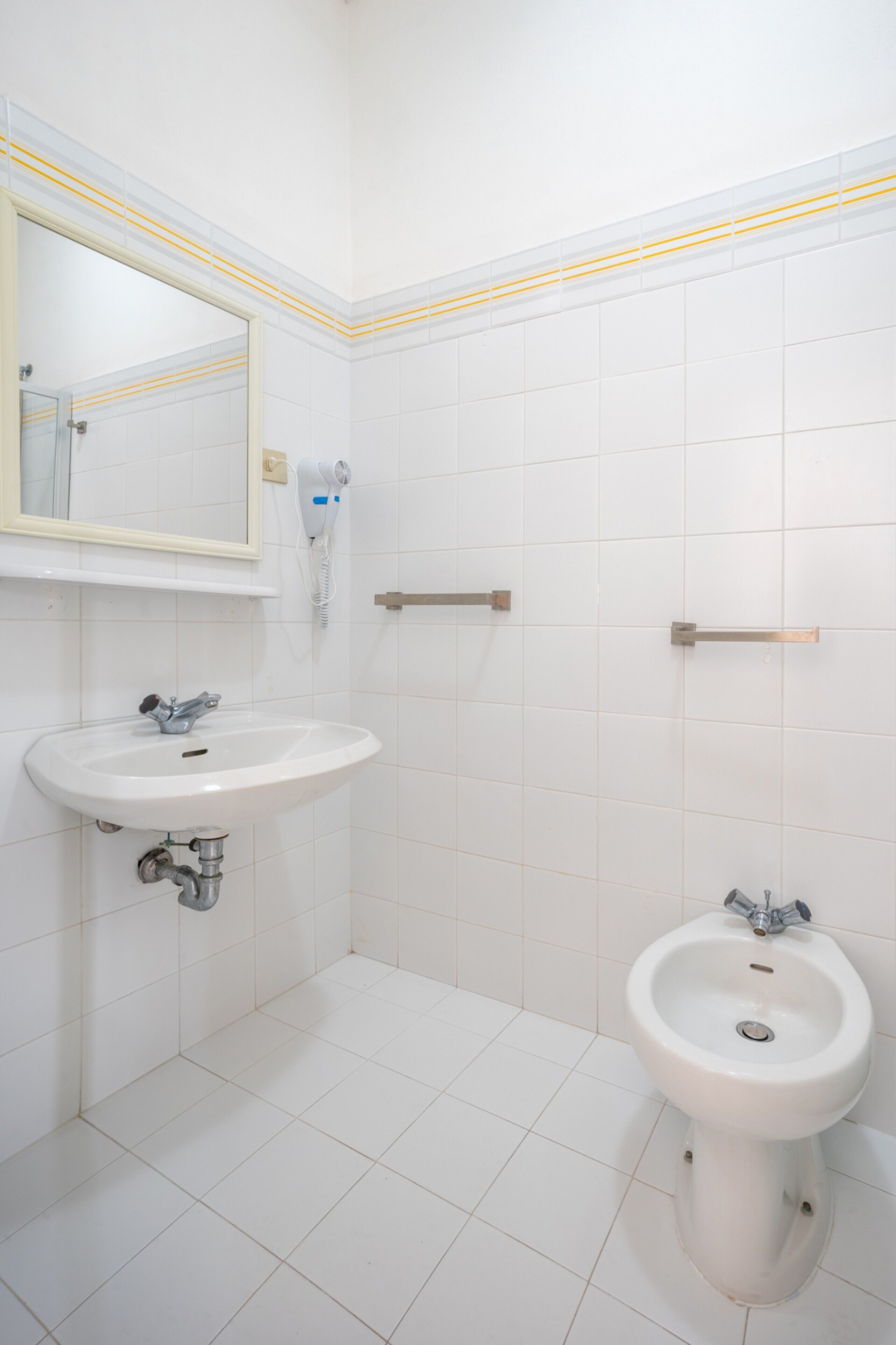 Een badkamer met een witte wasbak, een spiegel, een toiletbril en een handdoekhouder.