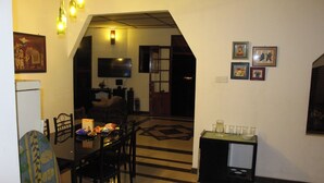 Un comedor con una mesa dispuesta para dos, un televisor montado en la pared y un pequeño mueble con cristalería.