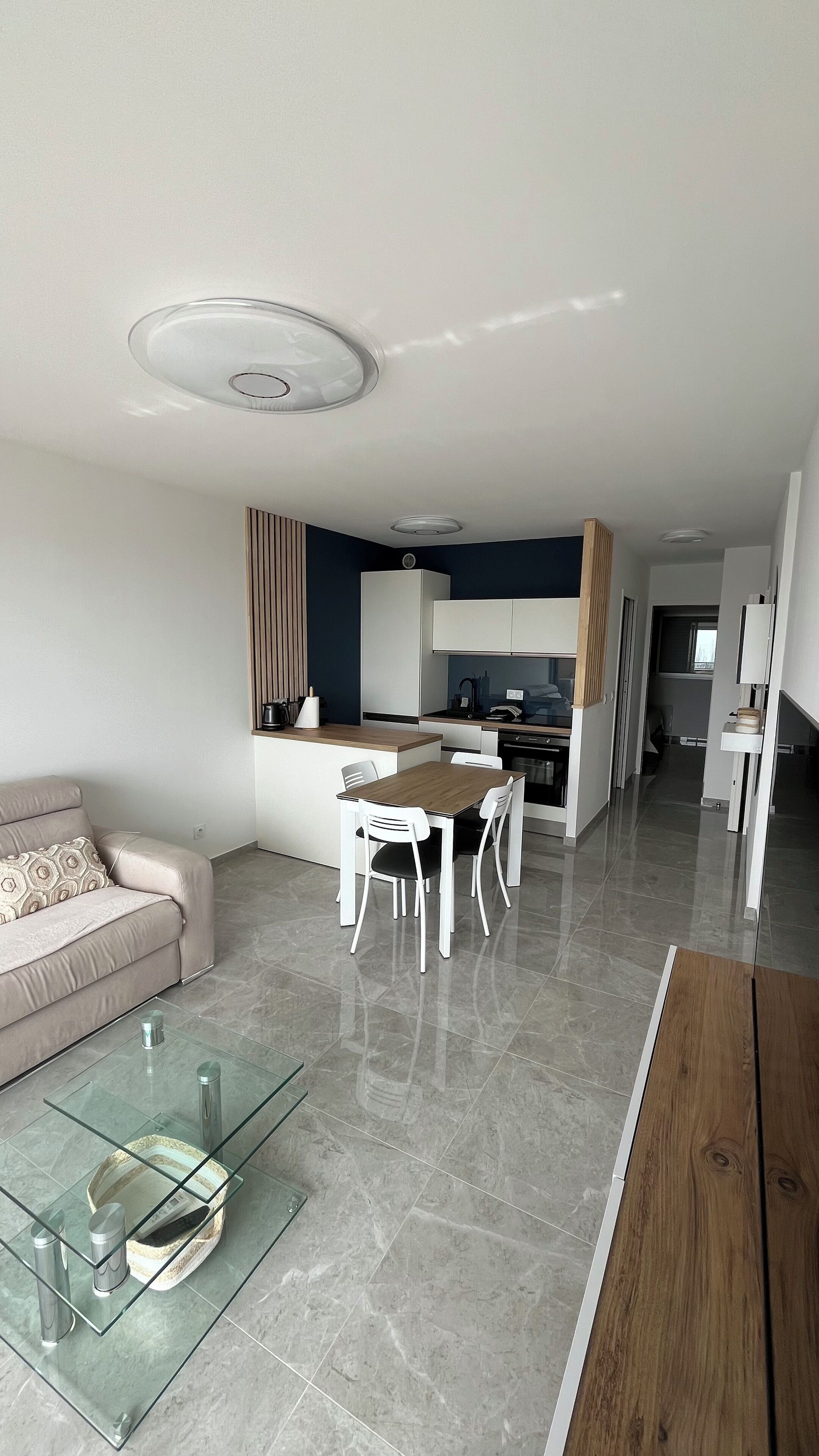 A modern living room with a glass coffee table, a sofa, and a dining area with a table and chairs.