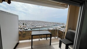 A balcony with a view of a marina filled with boats, a table, and a chair. - Sea view apartment (Palavas-les-Flots)