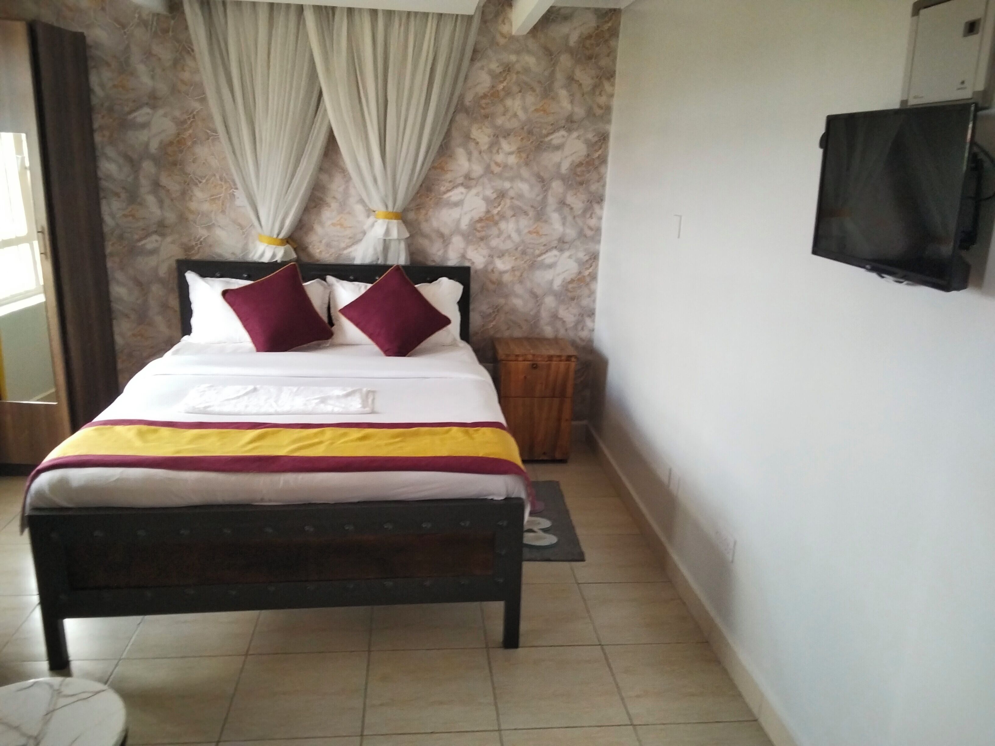 A bed with a headboard, pillows, a blanket, a bedside table, and a wall-mounted TV.