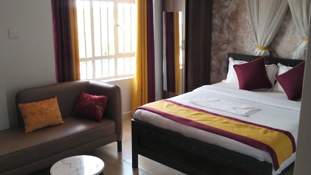 Une chambre d’hôtel avec un lit, un canapé, une petite table et une fenêtre avec des rideaux.