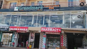 Un immeuble à plusieurs étages abritant divers commerces, notamment un magasin de meubles, une pharmacie et un salon de coiffure.