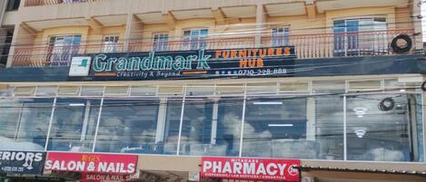 A multi-story building with various businesses including a furniture store, a pharmacy, and a salon.