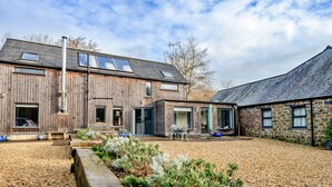 Un bâtiment moderne doté d’une façade en bois, de grandes fenêtres et d’une cour intérieure recouverte de gravier.