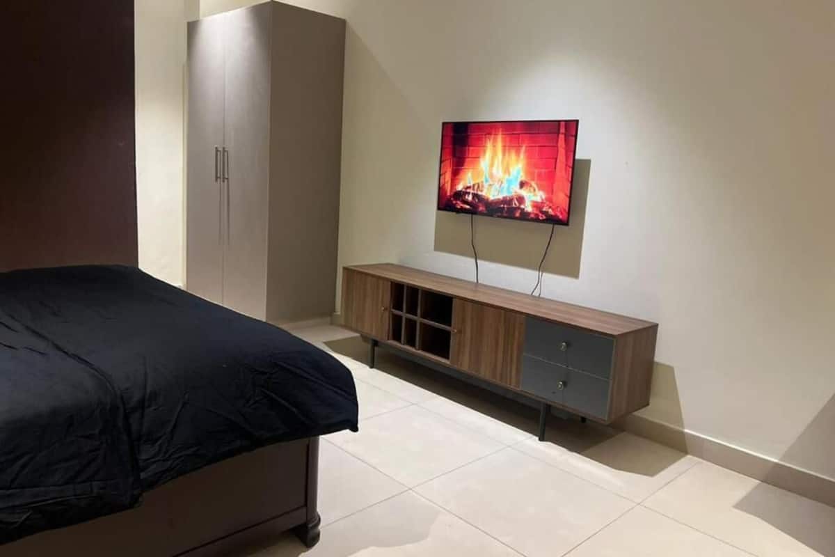 Ein Schlafzimmer mit Bett, Kleiderschrank, Wandfernseher und Holzschrank.