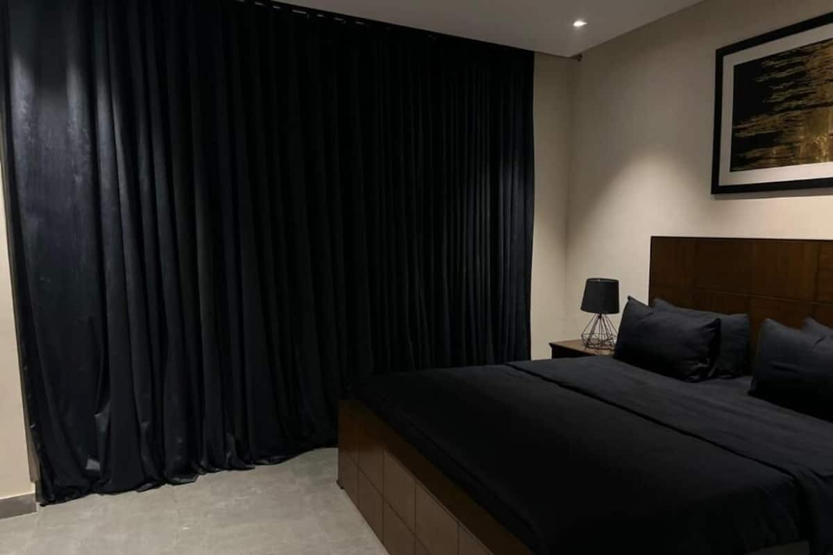 Ein Schlafzimmer mit einem großen Bett, einem Nachttisch, einer Lampe und einem Bild an der Wand.