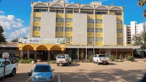 A hotel with a yellow facade, multiple balconies, and a sign indicating it offers conference, accommodation, food, bar, entertainment, and weddings.