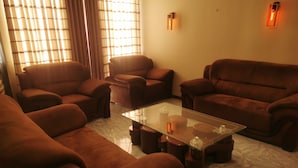 A living room with a glass coffee table, leather sofas, and a tiled floor.