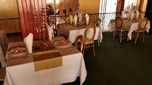 A restaurant with tables set for dining, featuring gold accents and white tablecloths.