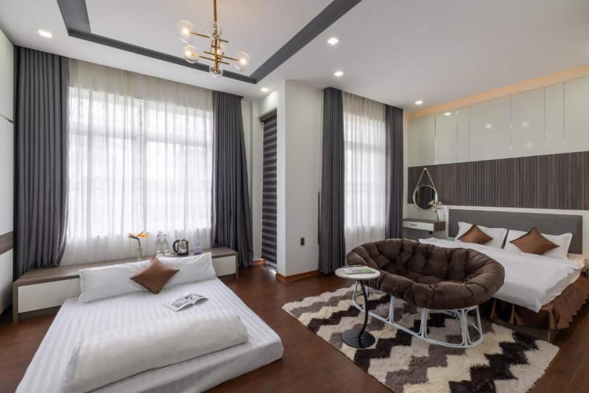 A modern hotel room with a large bed, a seating area, and a large window with curtains.