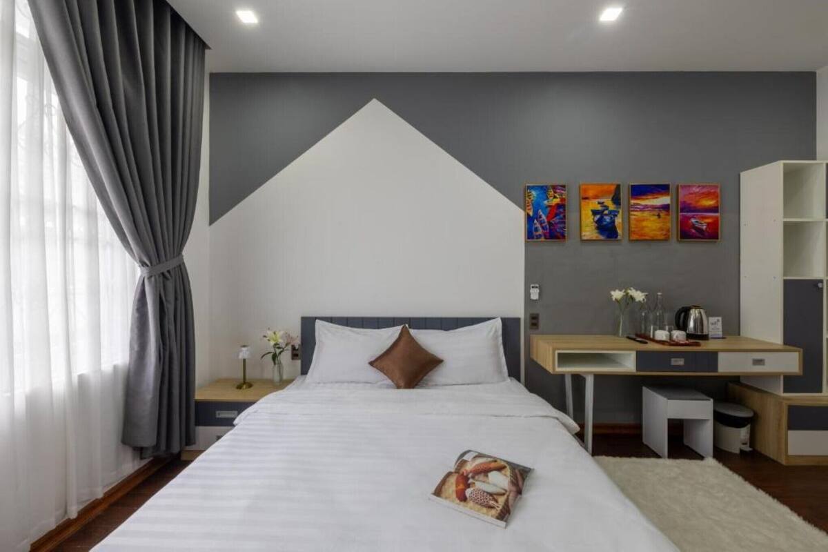 A modern hotel room with a bed, a desk, and a small seating area.