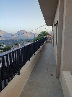 A balcony with a view of mountains and a red-roofed building in the distance. - Axos Getaway: Cozy Junior Apartment for Couples or Solo Travelers (Axos, Mylopotamos)