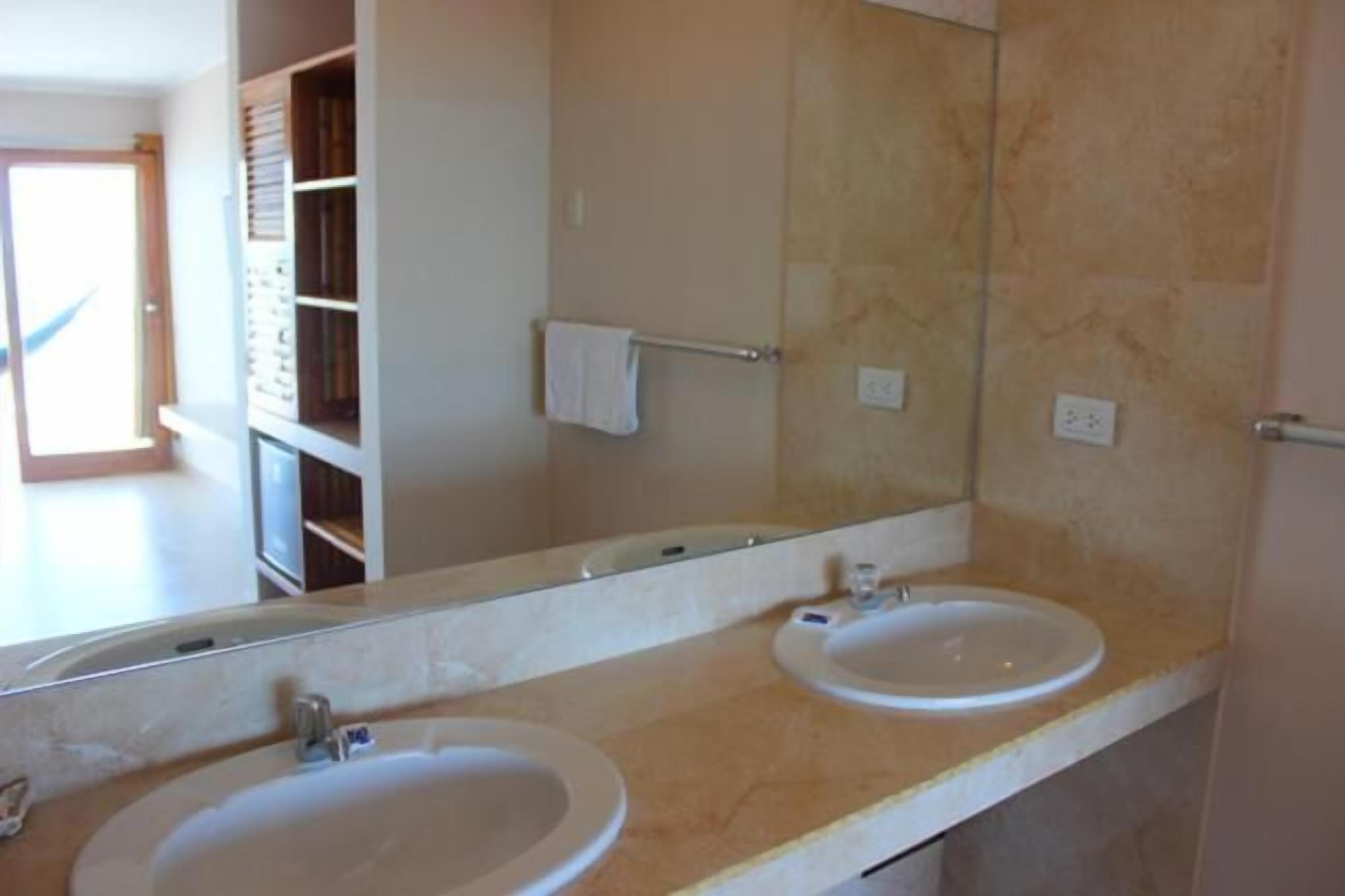 A bathroom with two sinks, a large mirror, and a towel rack.