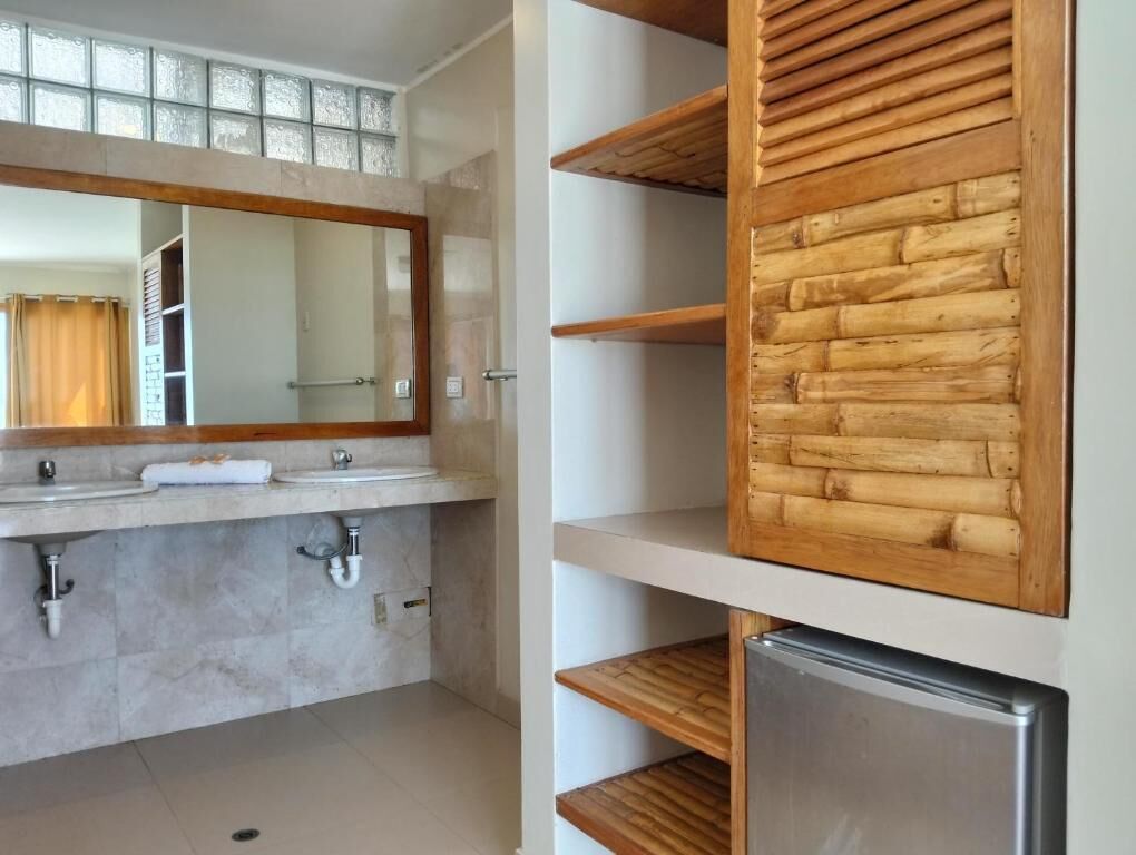 A bathroom with a large mirror, two sinks, a towel, and a wooden shelf unit.