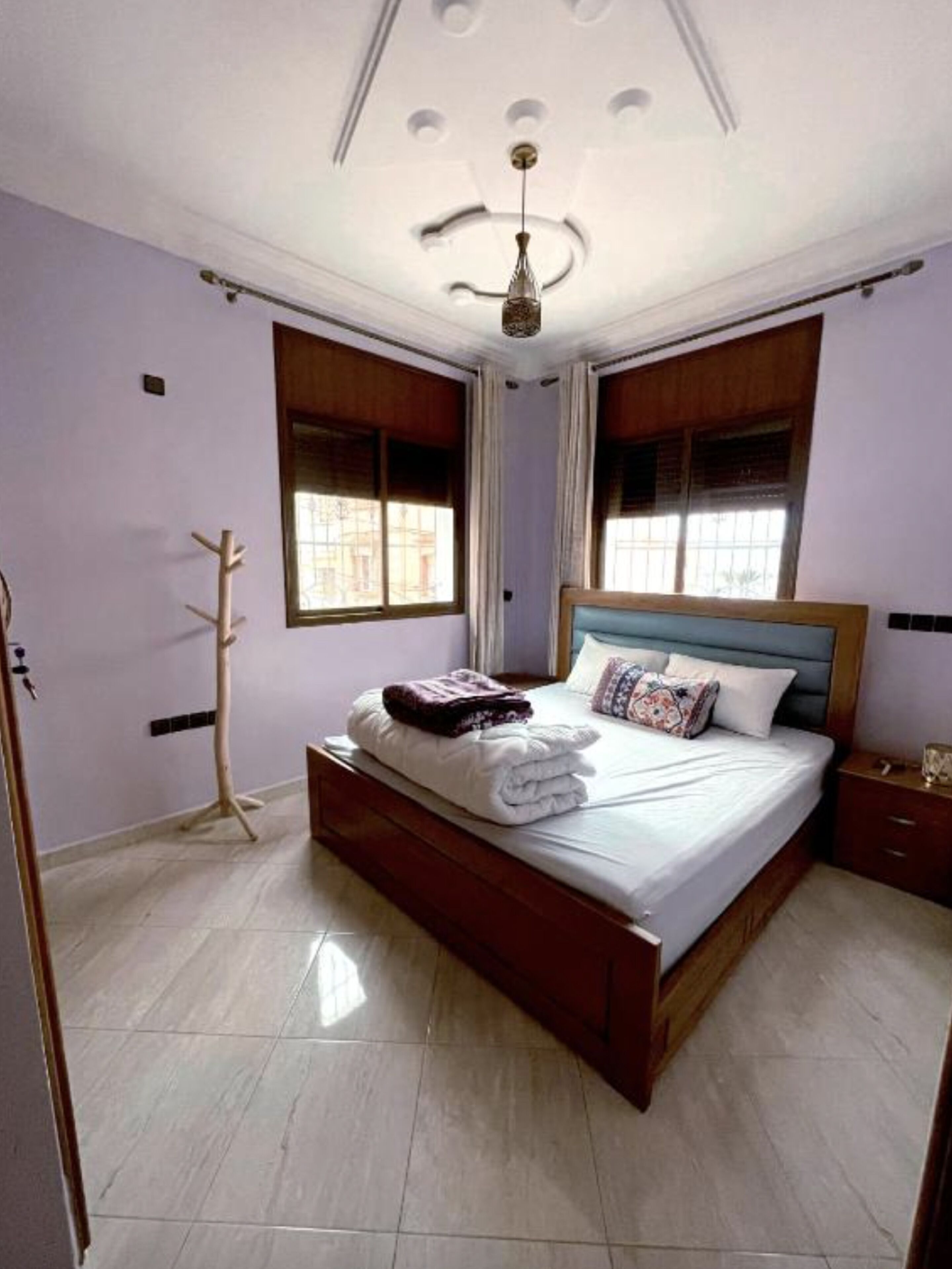 Un dormitorio con cama de madera, un calefactor independiente y una ventana con cortinas.