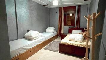 A compact bedroom with two single beds, a wooden ladder, and a small desk.