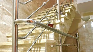 A modern staircase with stainless steel railings and beige marble walls. - tayri surf house (Aourir)