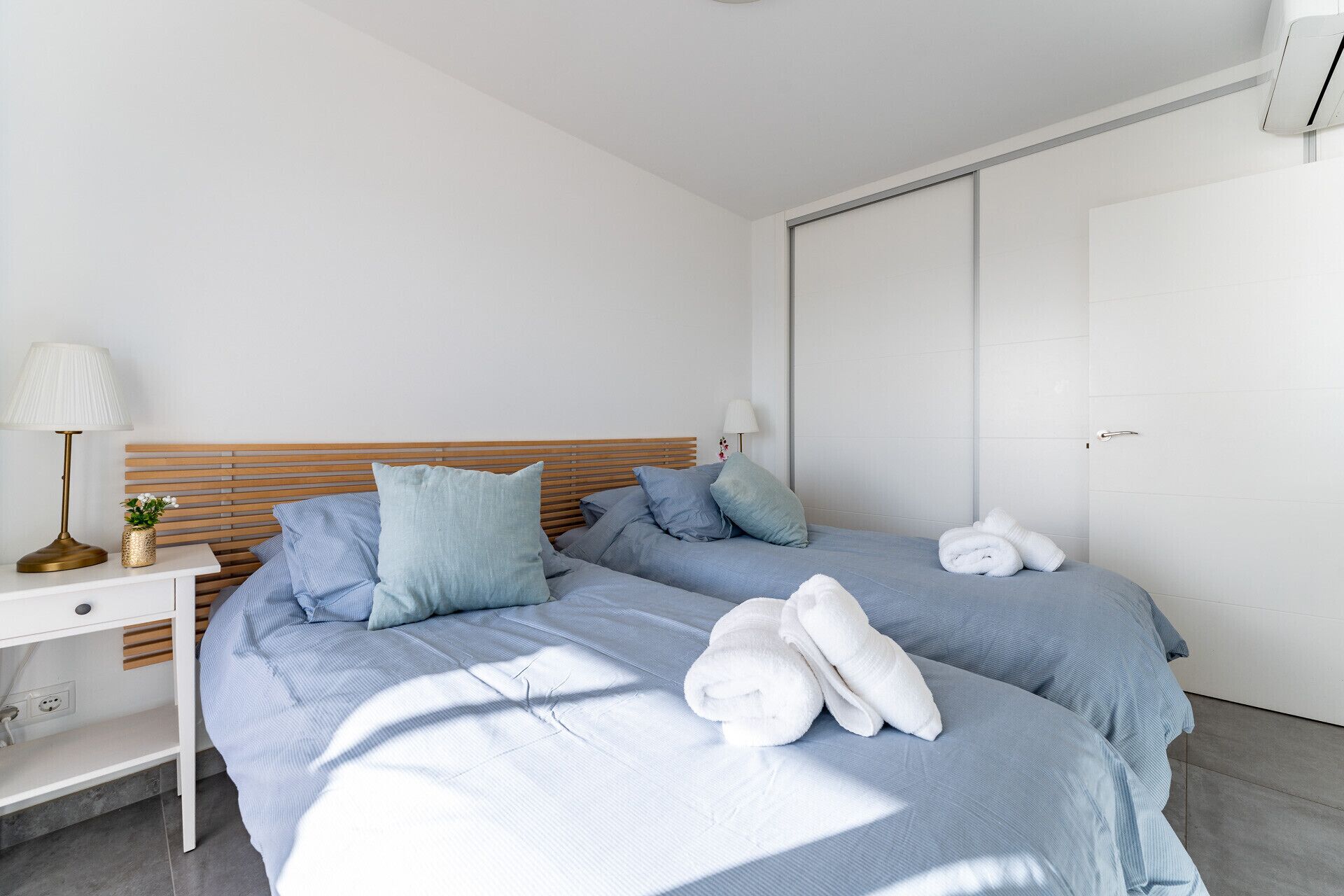 Un dormitorio moderno con dos camas, una mesita de noche y una mesilla.