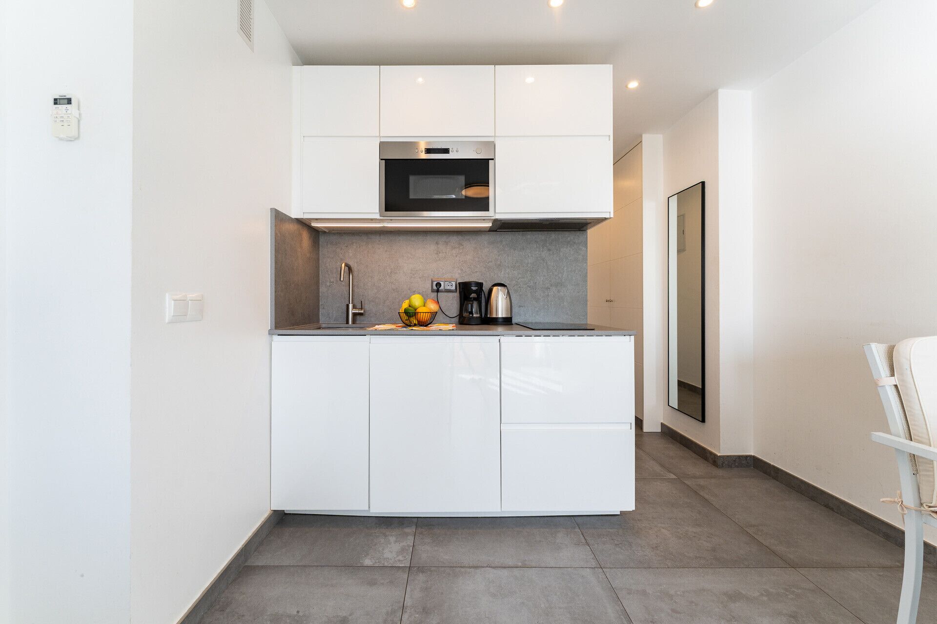 Een kleine keuken met witte kastjes, een roestvrijstalen oven en een magnetron.