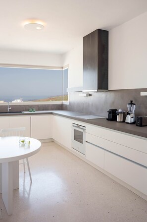 Eine moderne Küche mit Blick auf die Landschaft, einem weißen Tisch und einem Geschirrspüler.
