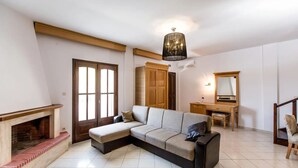 A living room with a sectional sofa, a fireplace, a wooden desk, and a mirror. - Beach Villa by Greek Pride (Skala Fourkas)
