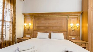 A hotel room with a large bed, two nightstands, a wooden headboard, and two wall-mounted lamps. - Beach Villa by Greek Pride (Skala Fourkas)