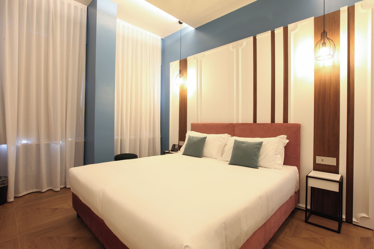 A neatly made bed with white linens, a wooden headboard, and two pillows.