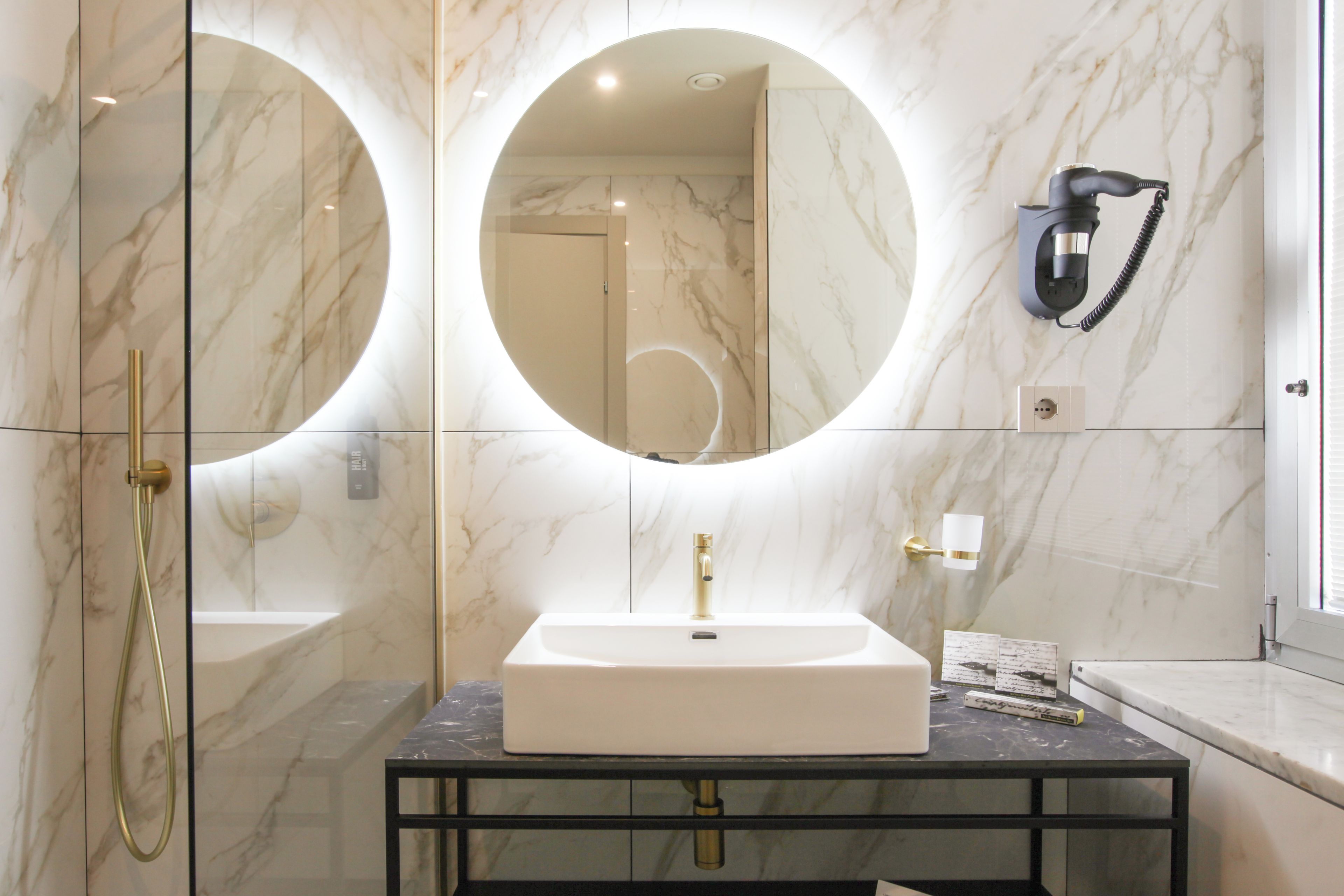 Une salle de bain avec un lavabo blanc, des robinetteries dorées et un grand miroir.