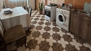 Uma cozinha compacta com área de refeições, fogão, máquina de lavar e pia.