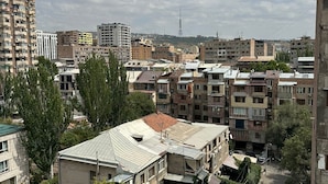 Uma área urbana densa, com edifícios residenciais de vários andares, ruas estreitas e alguma vegetação.
