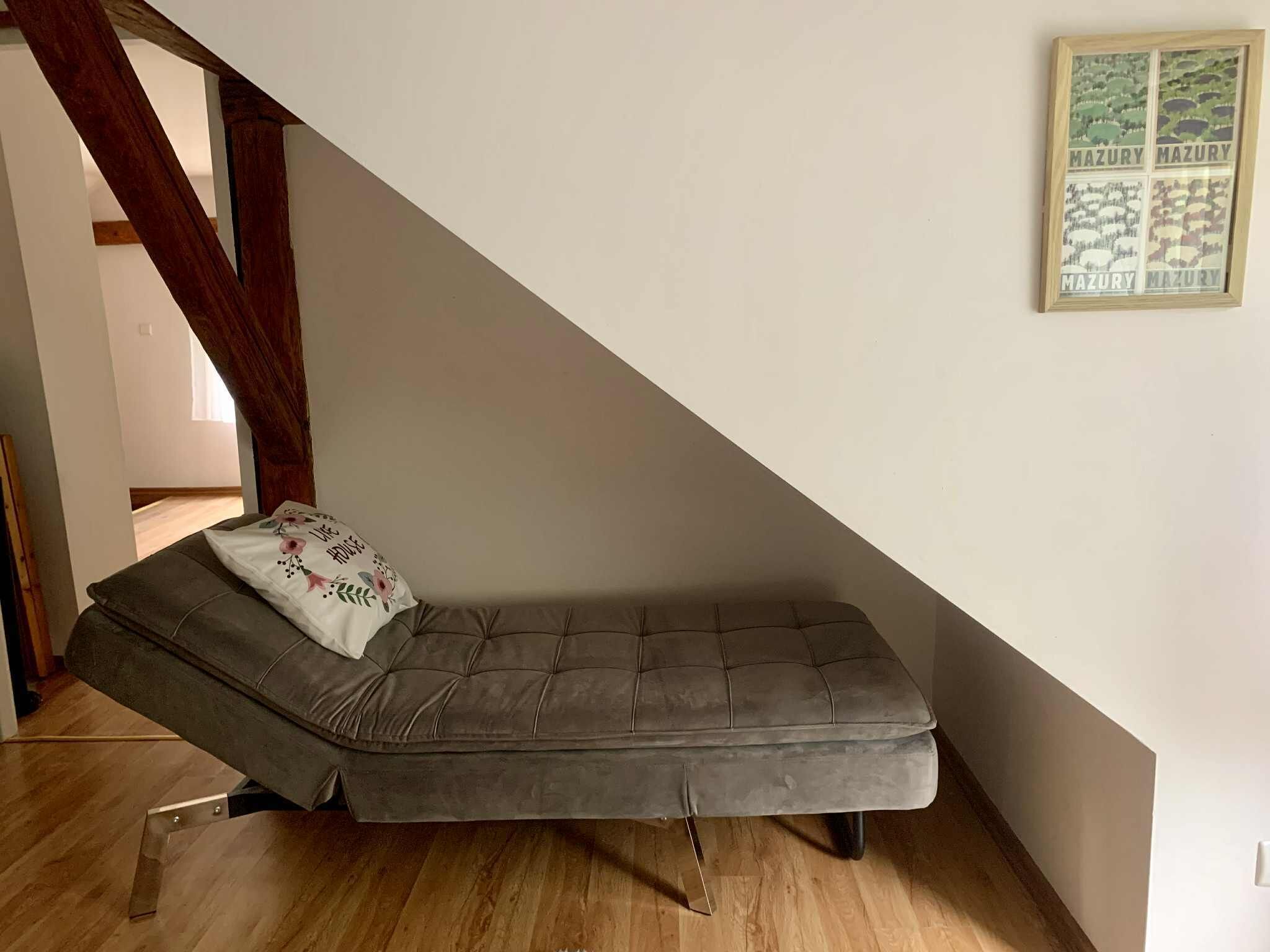 Une chambre de style « loft », avec un lit intégré, des poutres en bois et un tableau encadré au mur.
