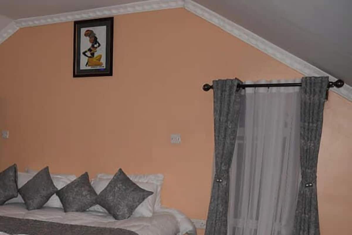 Une chambre à coucher avec un lit, un tableau encadré au mur et des rideaux.