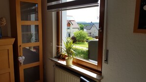 Huoneessa on ikkuna, josta avautuu näkymä asuinalueelle, ikkunan alla on patteri ja huoneessa on myös puinen kaappi, jossa on lasiovet.
