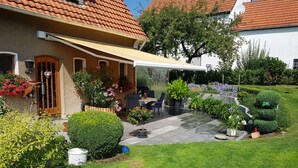 Talo, jossa on patio, ulkotila istumista varten ja hyvin hoidettu puutarha.