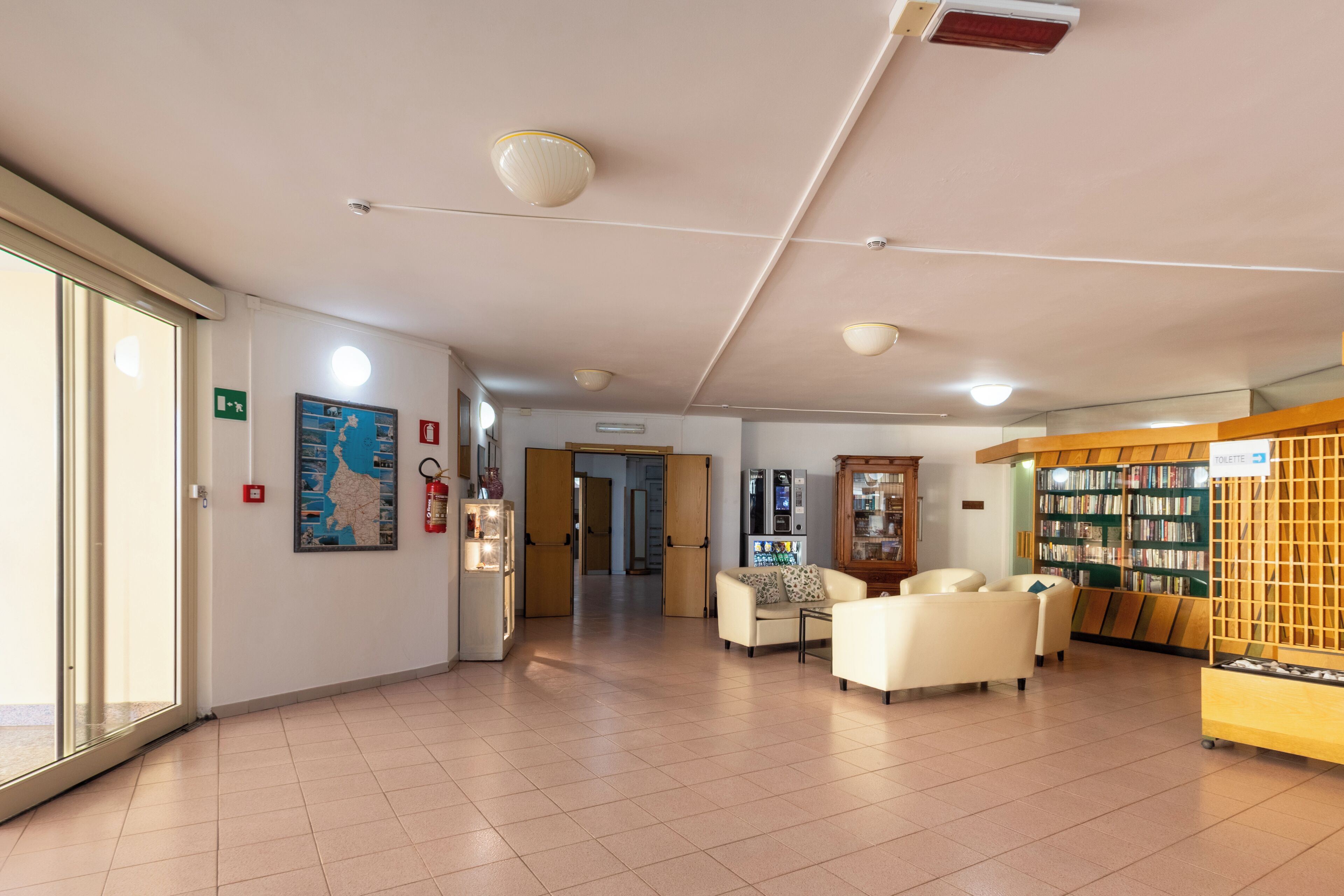 Un hall d’entrée spacieux, avec une carte affichée au mur, un comptoir de réception et un espace détente avec des sièges.