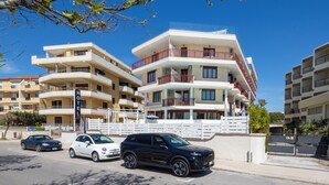 Ein mehrstöckiges Hotel mit Balkonen, einem Parkplatz und blauem Himmel.
