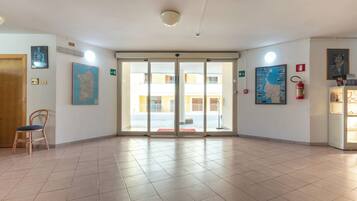 A hotel lobby with a tiled floor, a wooden chair, a fire extinguisher, and a map on the wall.