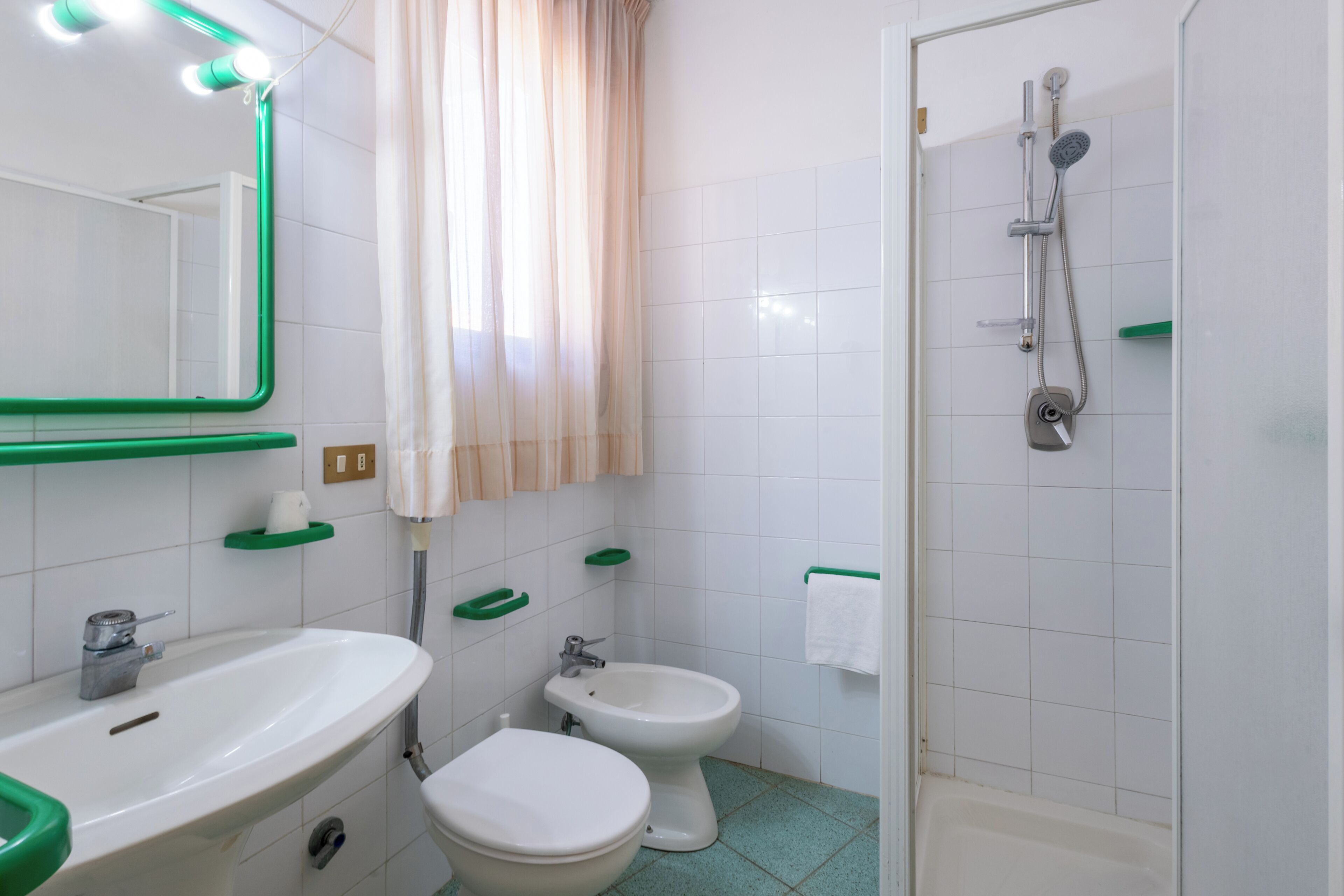 A bathroom with a sink, toilet, bidet, and shower.