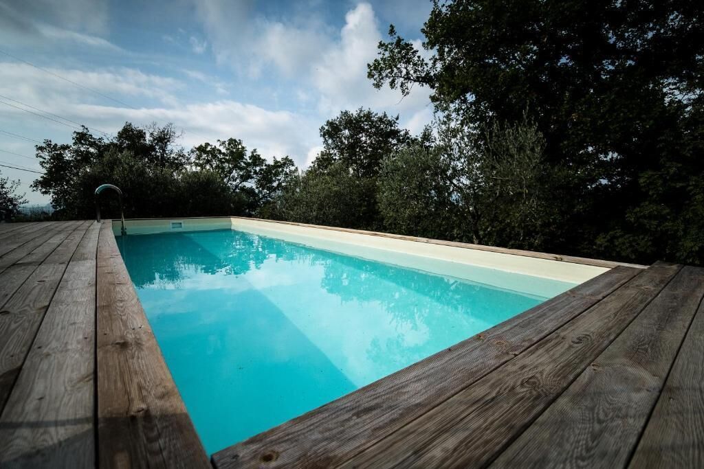 Eine Holzterrasse umgibt einen rechteckigen Pool mit klarem, blauem Wasser.