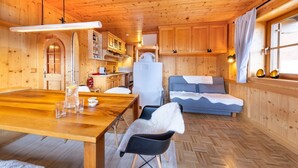 L’intérieur d’une cabane en bois comprend une table à manger, un canapé et un coin cuisine.